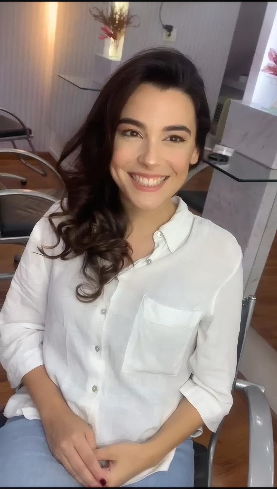 Cliente sorrindo na cadeira do Visage Studio Hair, com cabelo e maquiagem finalizados