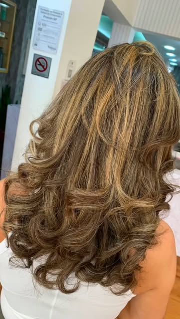 Cabelo castanho com luzes douradas e cachos modelados